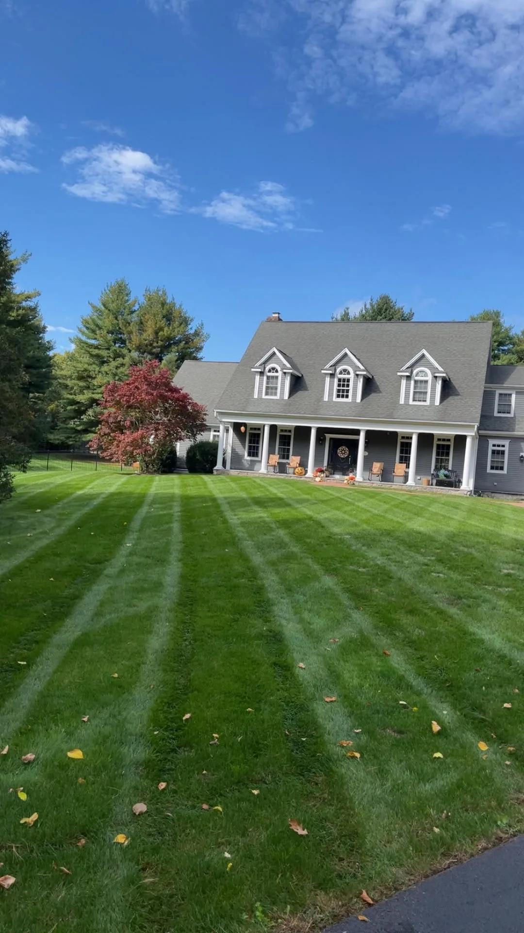 A wide, freshly mowed lawn with crisp mowing stripes in front of a large colonial home in Easton, Massachusetts.
